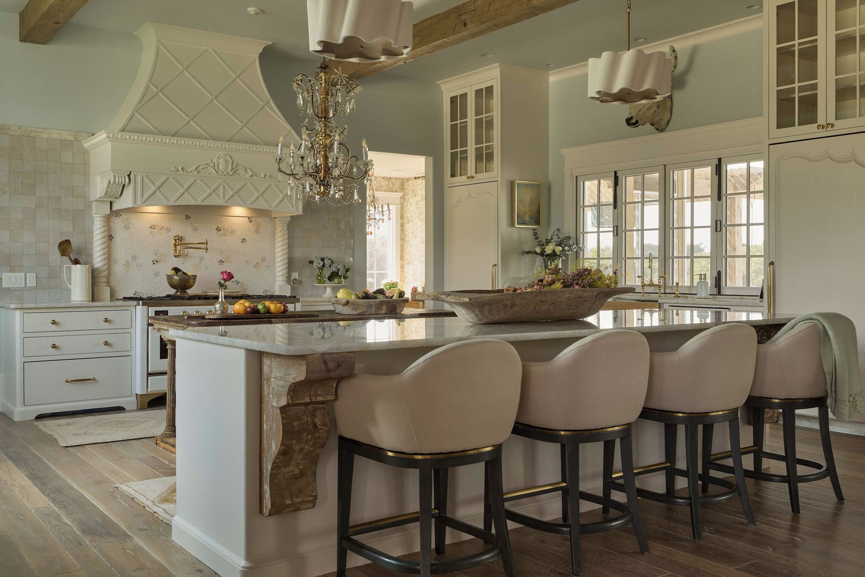 A spacious kitchen with a large island, bar stools, and a chandelier.