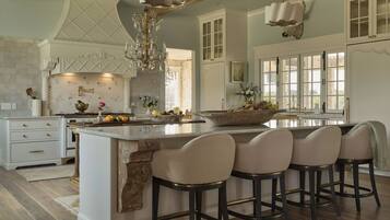 A spacious kitchen with a large island, bar stools, and a chandelier.