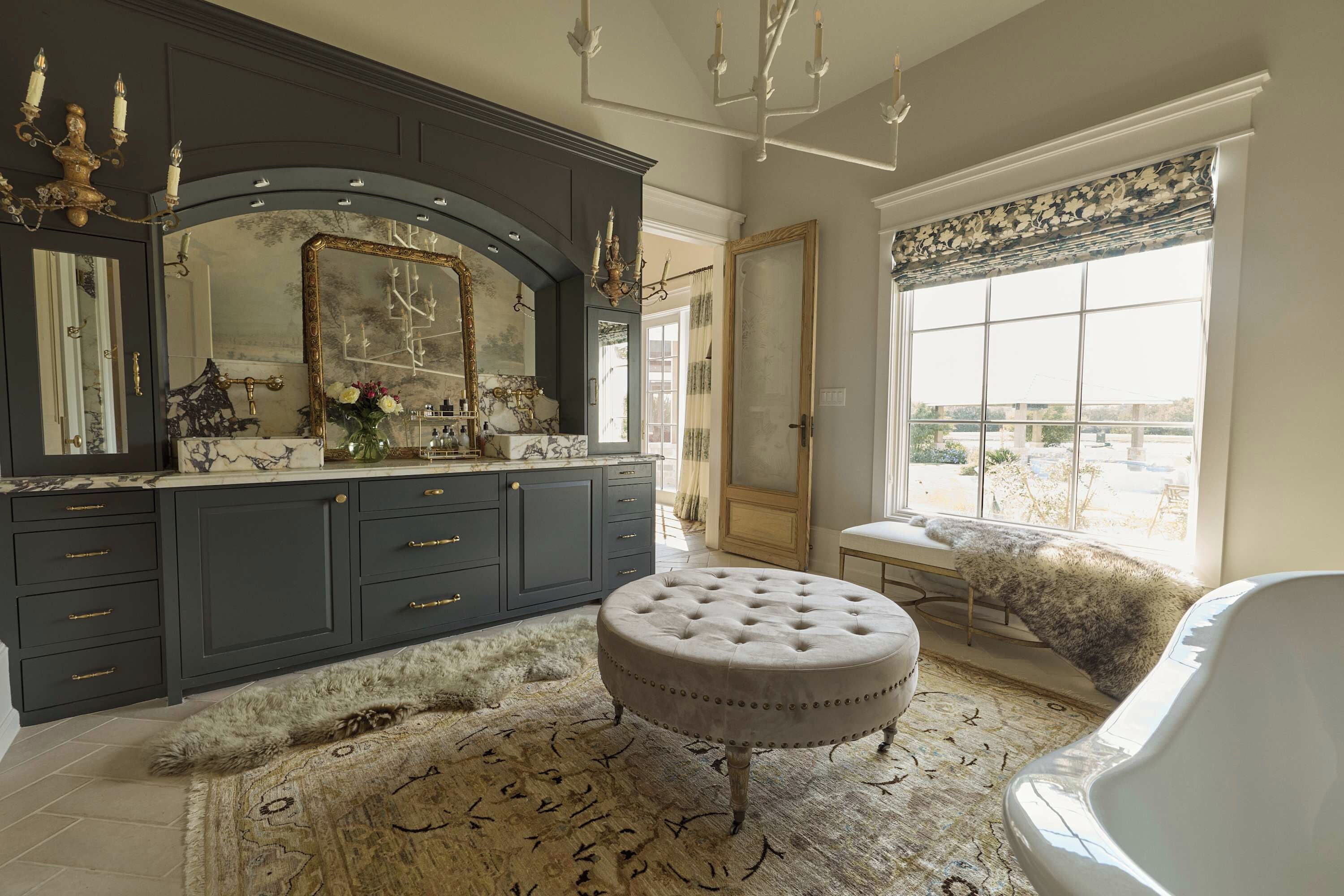 A luxurious bathroom with a large mirror, dark cabinetry, and a fluffy rug.