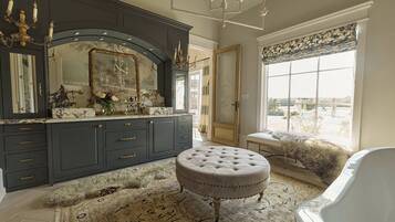 A luxurious bathroom with a large mirror, dark cabinetry, and a fluffy rug.