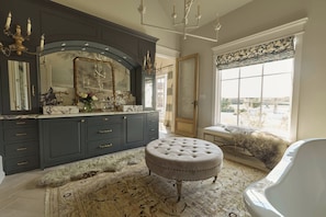 A luxurious bathroom with a large mirror, dark cabinetry, and a fluffy rug. - Hope Ranch | Lux Estate w/ Resort Style Amenities (Round Top)