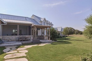 Ein Haus mit überdachter Terrasse, Steinstufen und Rasen.