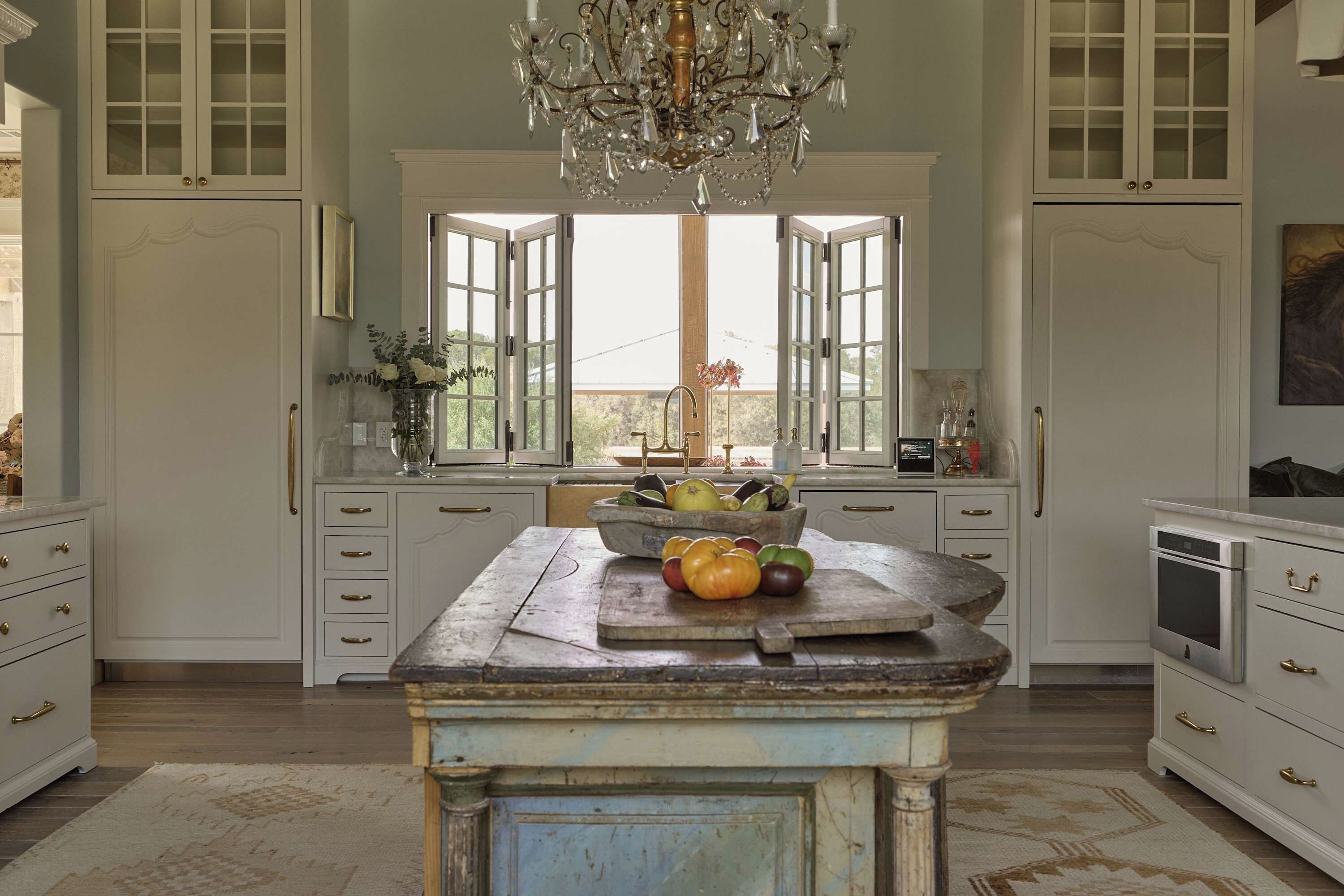 A kitchen with a central island, double doors, and a chandelier.