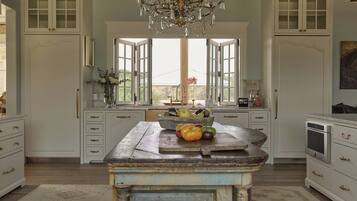 A kitchen with a central island, double doors, and a chandelier.