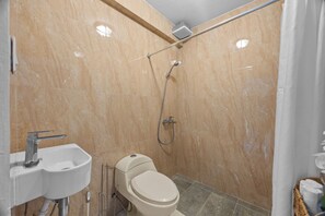 Et badeværelse med toilet, håndvask og brusebad.