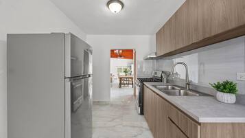 Cozinha moderna com eletrodomésticos de aço inoxidável, armários de madeira e piso de mármore.