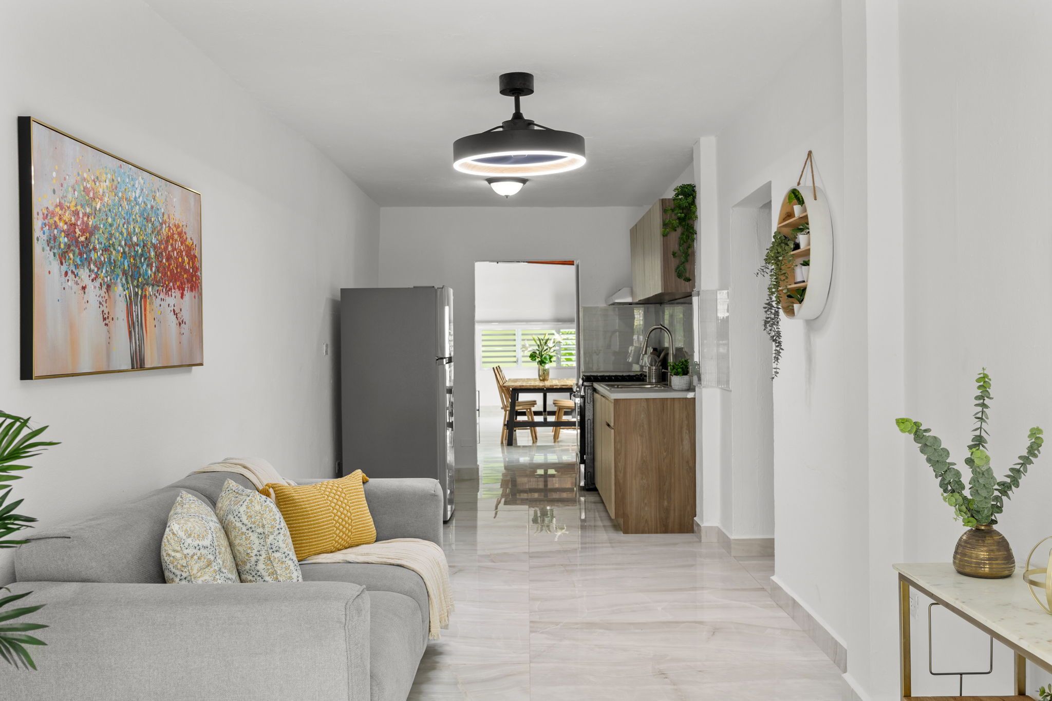 En moderne stue med en grå sofa, et billede og en loftlampe.