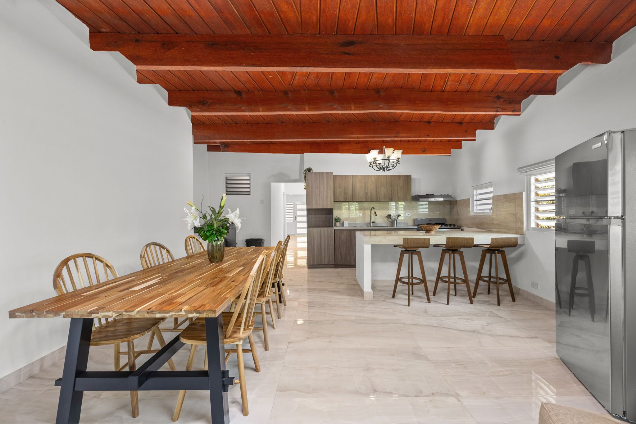 A modern kitchen with a central island, wooden dining table, and chairs.