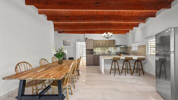 A modern kitchen with a central island, wooden dining table, and chairs.