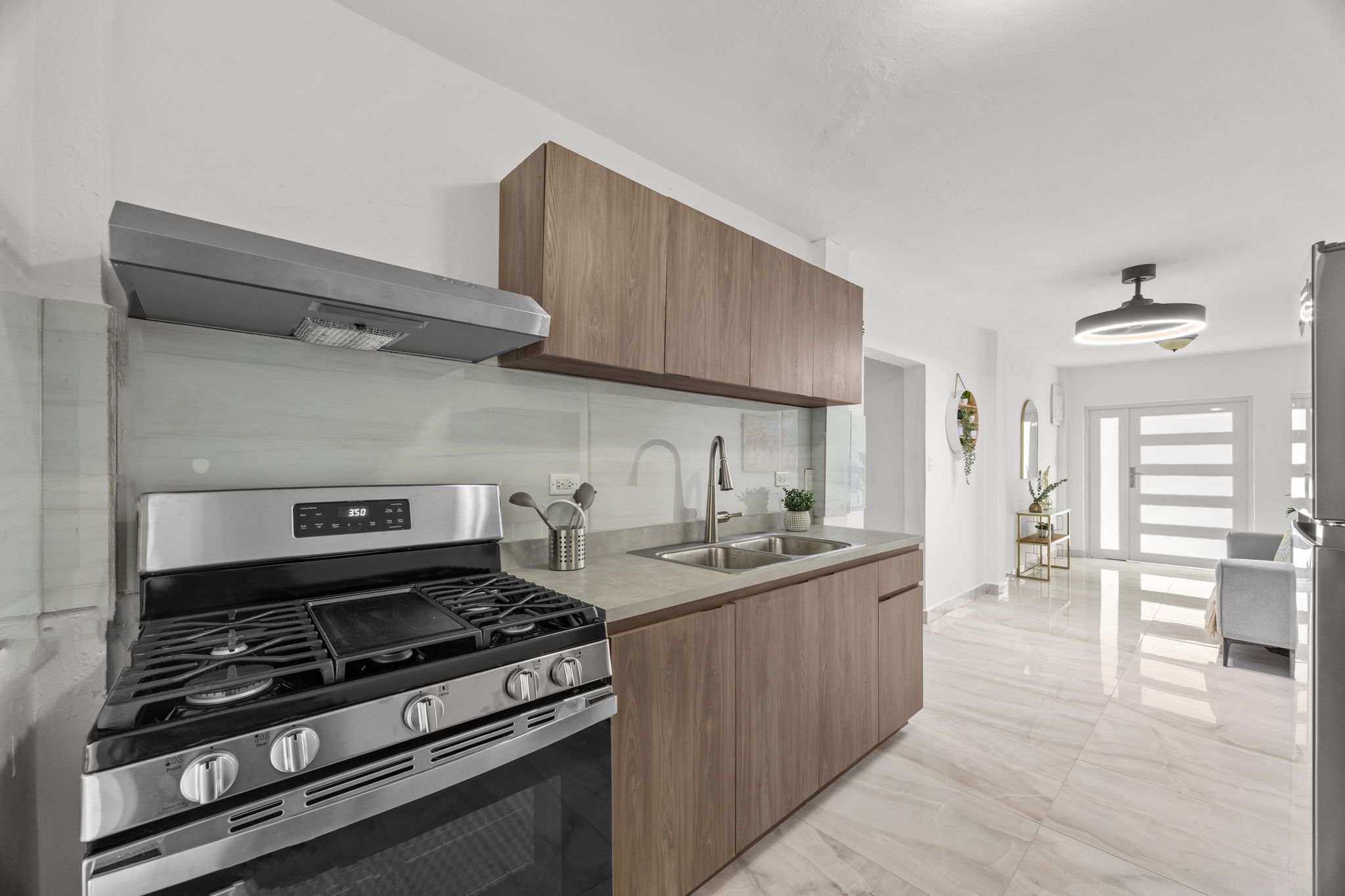 A modern kitchen with a stainless steel stove, wooden cabinets, and a large window.