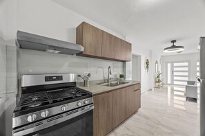 A modern kitchen with a stainless steel stove, wooden cabinets, and a large window.