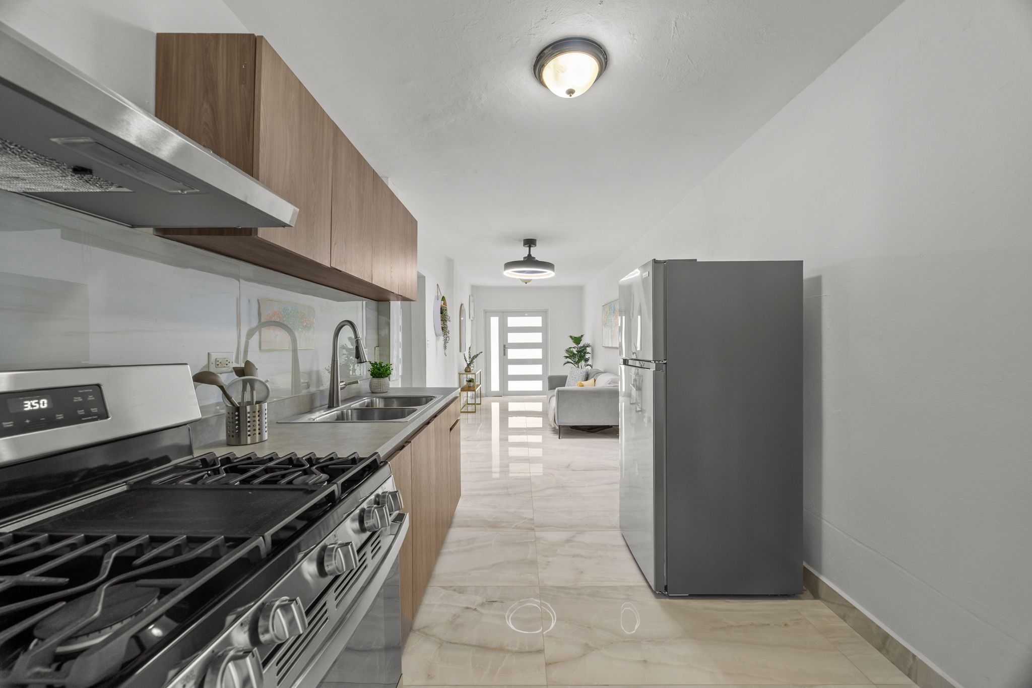 A modern kitchen with a stove, sink, and refrigerator.