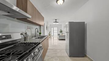 A modern kitchen with a stove, sink, and refrigerator.