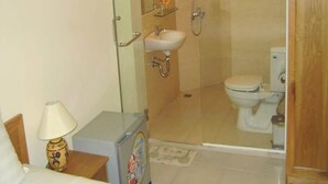 Un baño pequeño y funcional con ducha, inodoro y lavamanos.