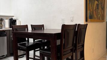 A dining area with a marble floor, a dark wooden table, and four chairs.