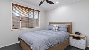 Ein Schlafzimmer mit einem Bett, einem Nachttisch, einer digitalen Uhr und einem Deckenventilator.