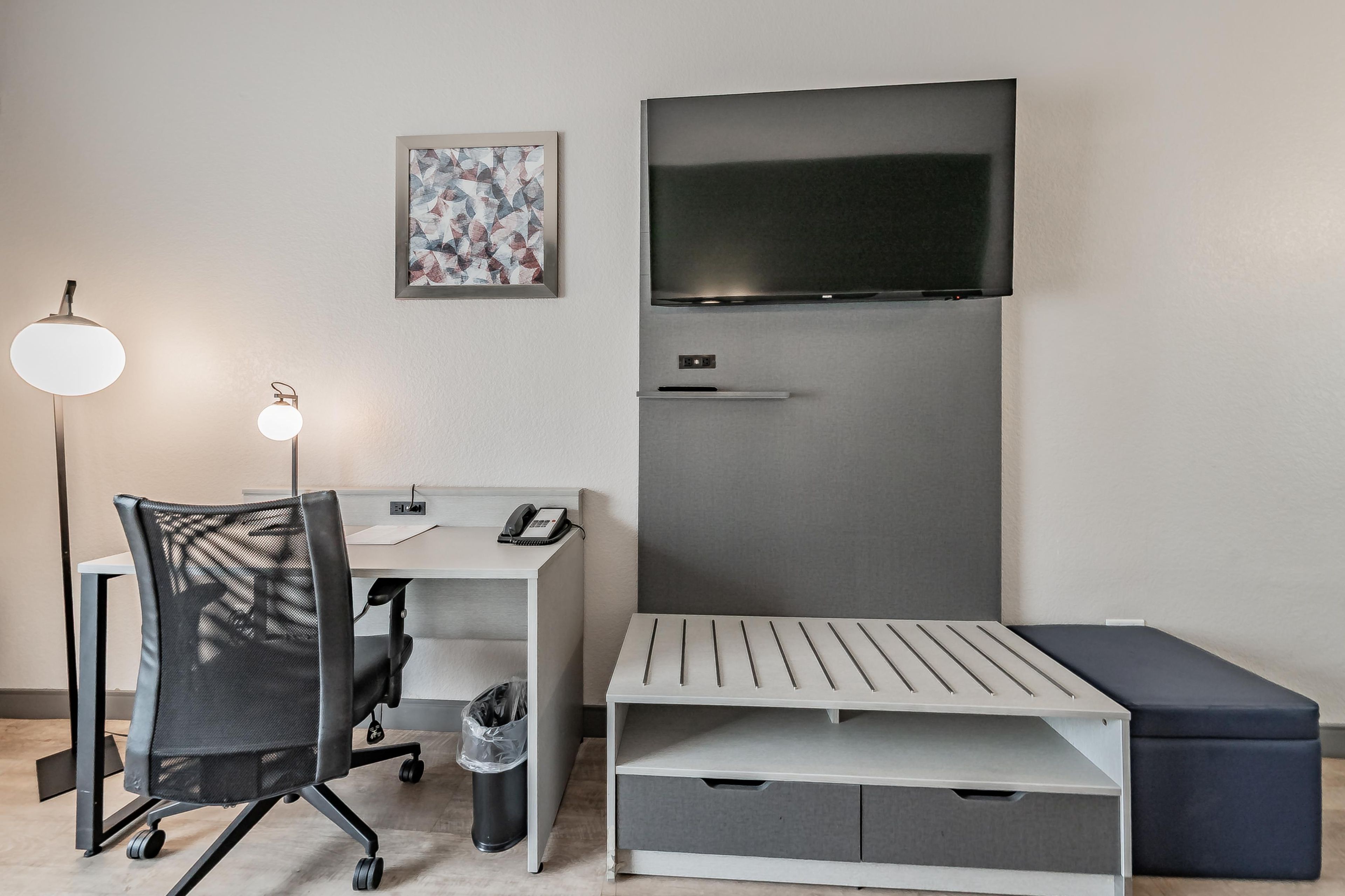 A modern room with a desk, chair, and a flat-screen TV mounted on the wall.