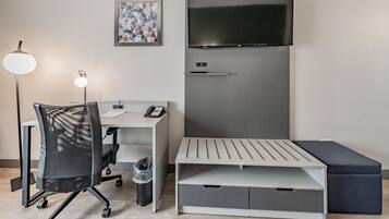 A modern room with a desk, chair, and a flat-screen TV mounted on the wall.