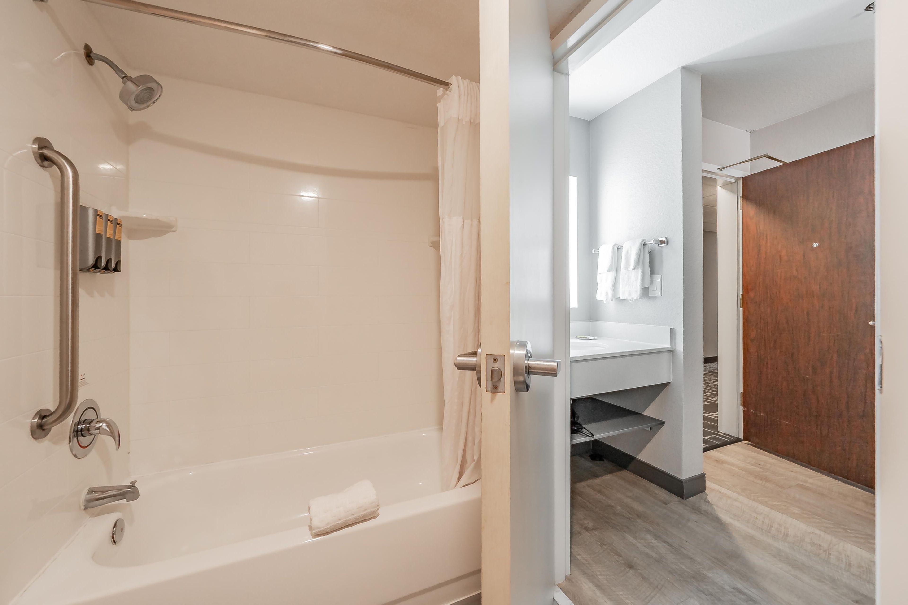 Une salle de bain moderne dotée d’une douche à l’italienne, de barres d’appui et d’un porte-serviettes.