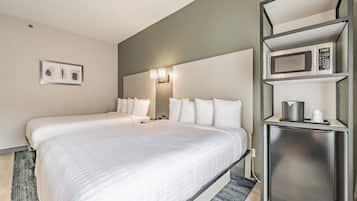 A hotel room with two beds, a microwave, a coffee maker, and a framed picture on the wall.