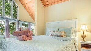 A bedroom with a large bed, a nightstand with a lamp, and a window with curtains. - Pine Hollow Hideout: Access to Canadarago Lake (Richfield Springs)