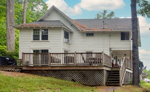 A two-story house with a wooden deck and a small porch.
