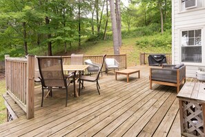 A wooden deck with outdoor furniture including chairs, a table, and a grill.