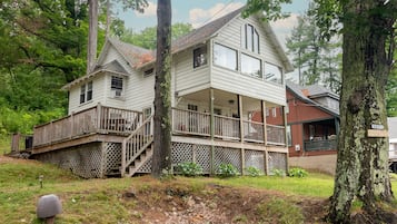 A two-story house with a wooden deck and a covered porch.