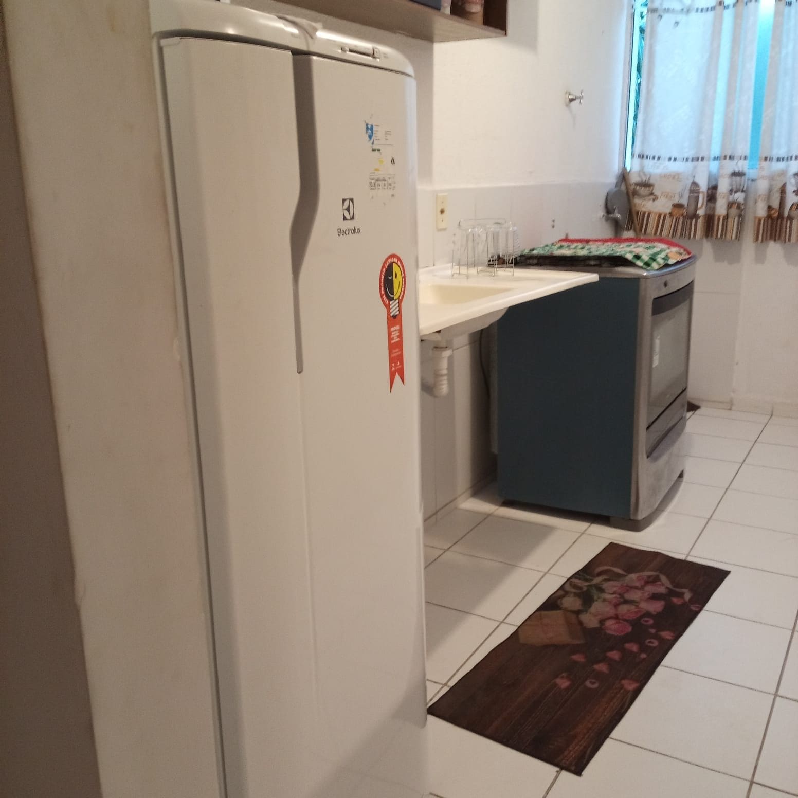 Una cucina con frigorifero bianco, forno blu e pavimento piastrellato.