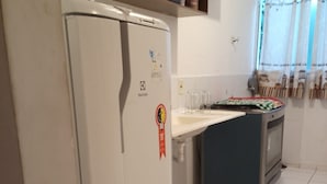 A kitchen with a white refrigerator, a blue oven, and a tiled floor. - Apto Agua Marinha (Campos dos Goytacazes)