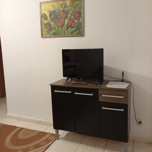 A room with a desk, a television, and a painting on the wall.