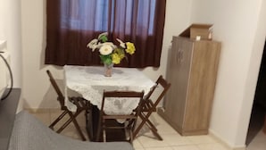 A small dining area with a table, chairs, and a cabinet. - Apto Agua Marinha (Campos dos Goytacazes)