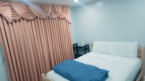 Ein Schlafzimmer mit einem Bett, einem Nachttisch, einer Lampe und einem Fenster mit Vorhängen.