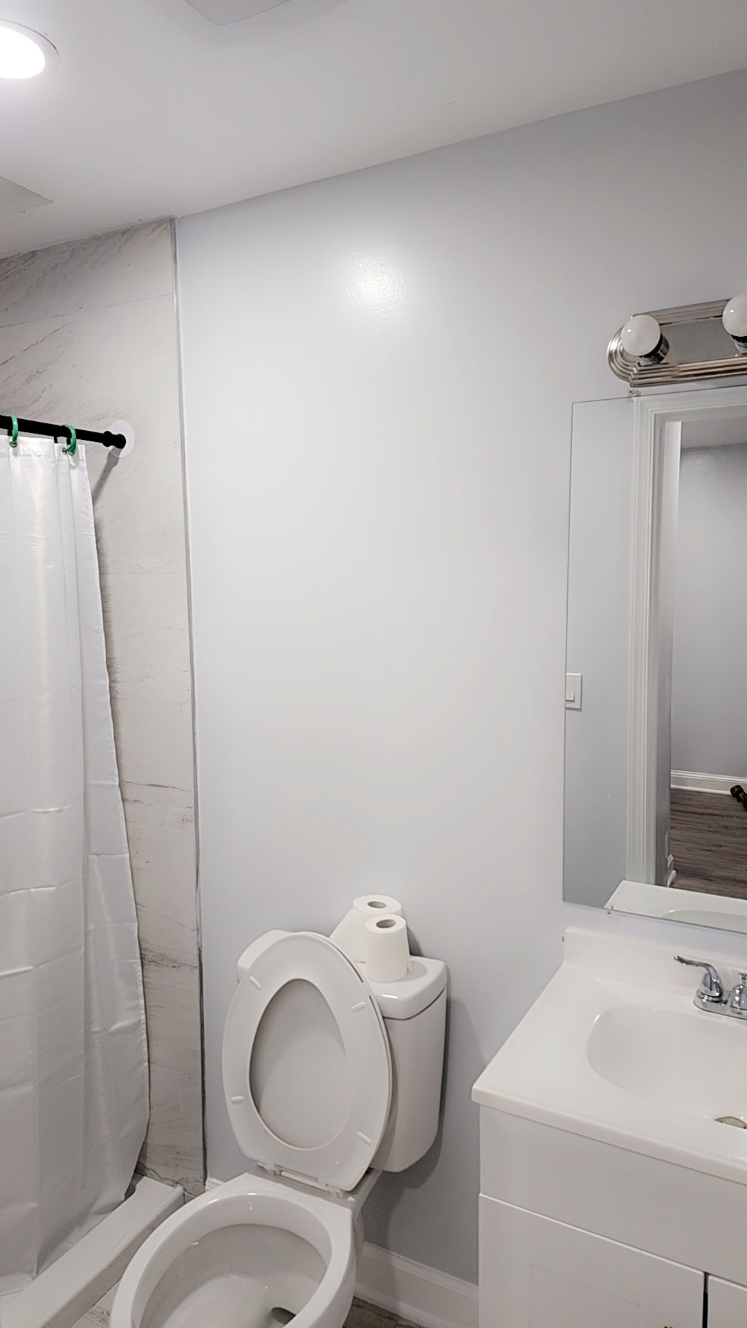 Een badkamer met een toilet, wastafel en douchegordijn.