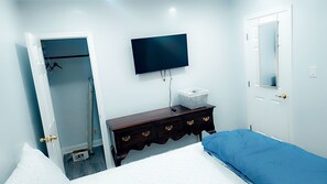 Un dormitorio con cama, cómoda, televisor y armario.