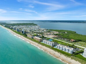 An aerial view of a coastal resort with beachfront properties, a marina, and a large body of water. - TIDE & SHELL - Remodeled Oceanfront Jensen Beach Retreat w/Private Beach & Pools (Jensen Beach)