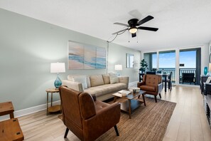 Ein Wohnzimmer mit einer Couch, Sesseln, einem Couchtisch und einem Deckenventilator.