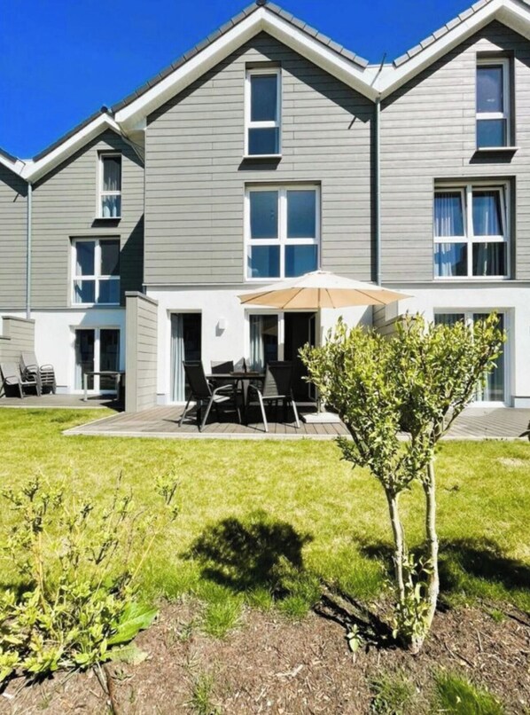 A residential building with a patio area featuring outdoor furniture and a small tree. - House No. 15, Fischerhus (Wangerland)