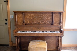 A grand piano with a wooden finish, positioned in a room with a door and a window. - Deer Creek Mountain Retreat (Heber City)