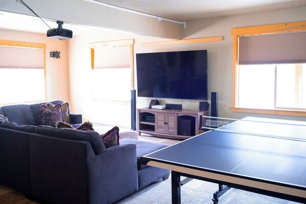 A living room with a sofa, a table tennis table, a television, and a speaker system. - Deer Creek Mountain Retreat (Heber City)