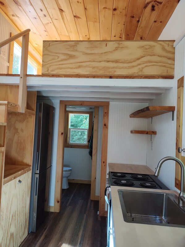 A compact kitchen with a built-in stove, a sink, and a window overlooking the outdoors.