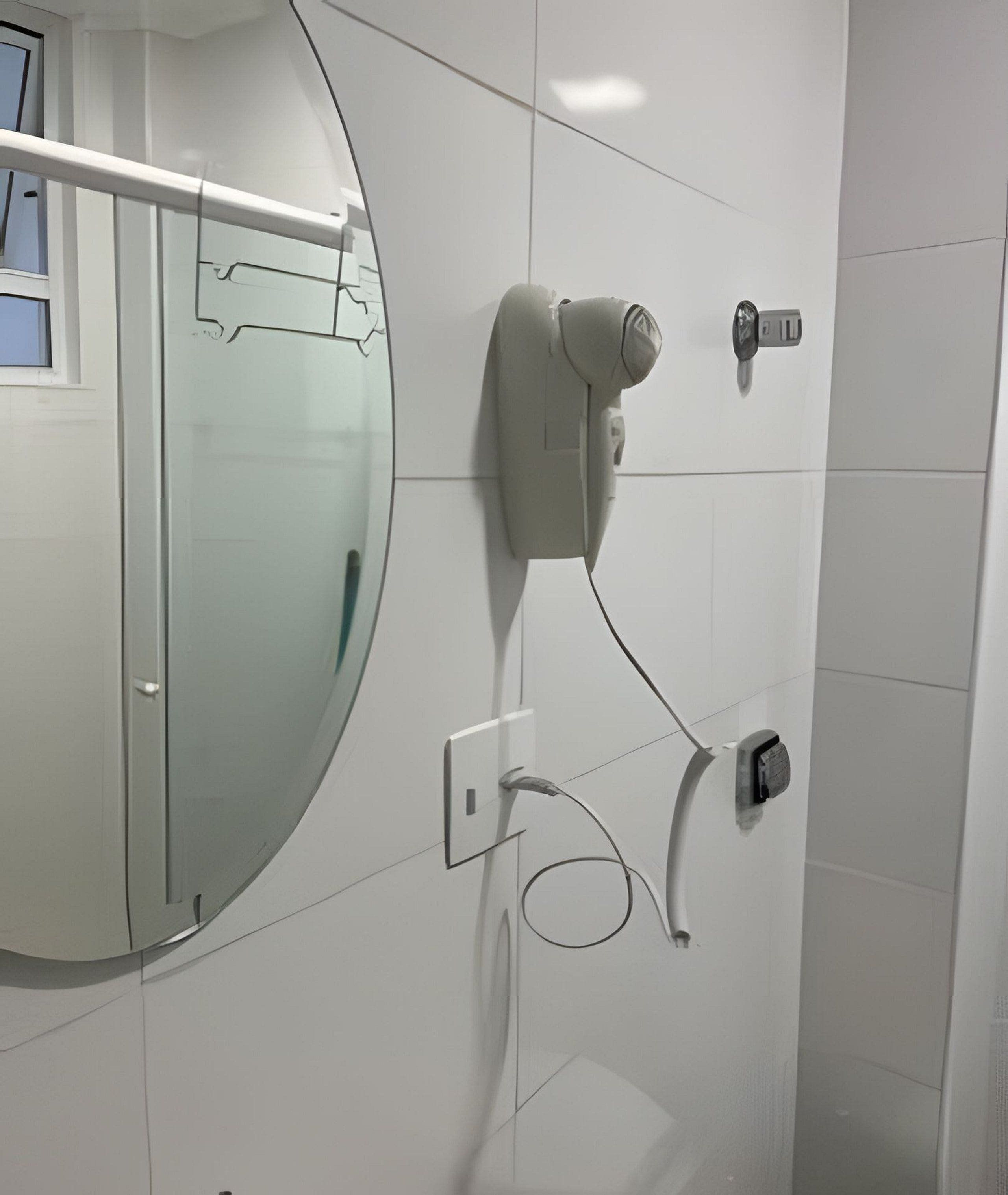 Un baño con un espejo grande, un dispensador de toallas y un secador de manos instalado en la pared.