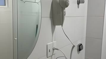 Un baño con un espejo grande, un dispensador de toallas y un secador de manos instalado en la pared.
