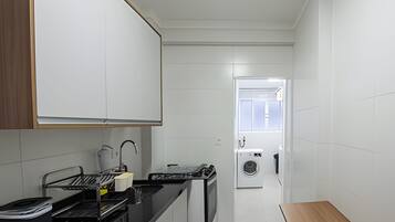 Una cocina moderna con encimera negra, pileta de acero inoxidable y horno integrado.