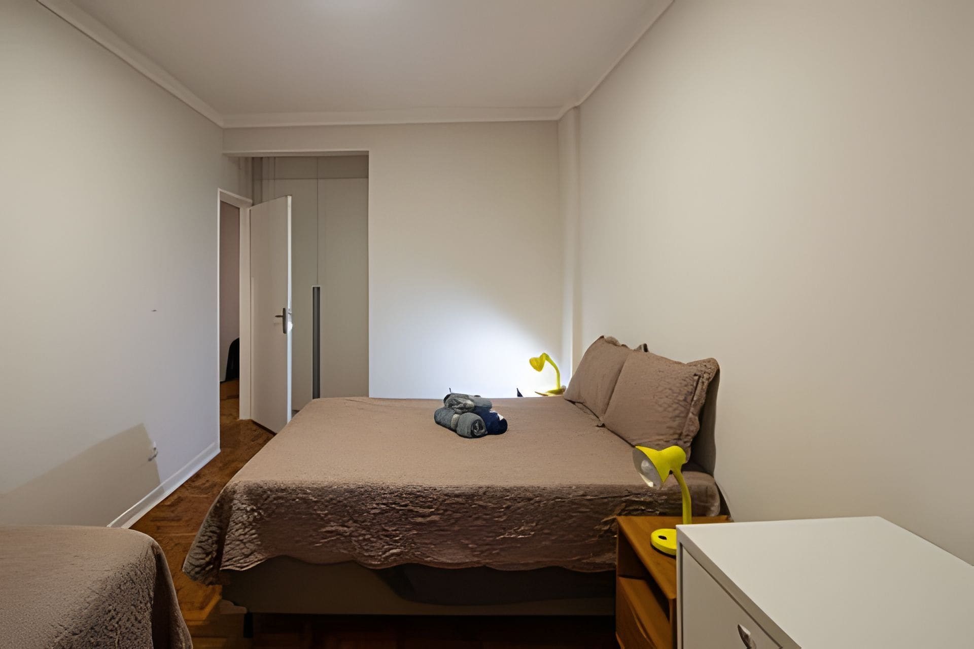 A bedroom with a bed, a bedside table, a lamp, and a wardrobe.