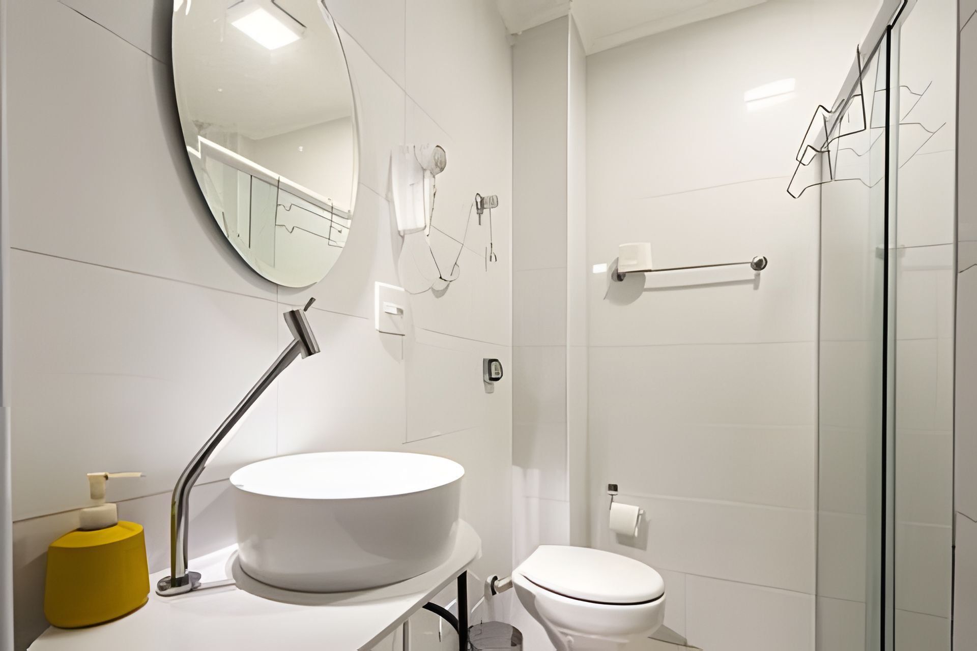 Un baño moderno con lavamanos, espejo y retrete blancos.