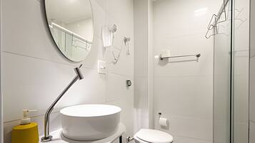 Un baño moderno con lavamanos, espejo y retrete blancos.