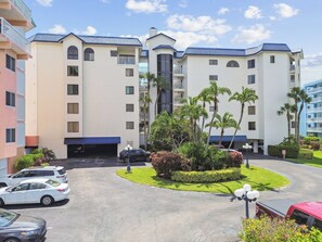 Ein mehrstöckiges Hotel mit Innenhof, Parkplatz und umliegendem Grün.