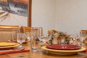 A dining table set with plates, glasses, and cutlery, with a decorative centerpiece and a painting on the wall. - Tranquil Southwest Apt with Traditional Courtyard (Mesa)