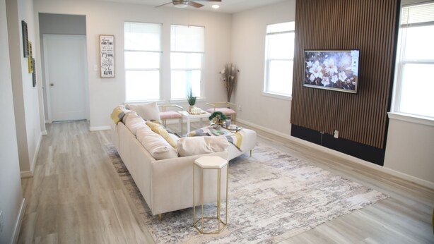 Un salon moderne avec un canapé, une table basse et un téléviseur à écran plat fixé au mur.